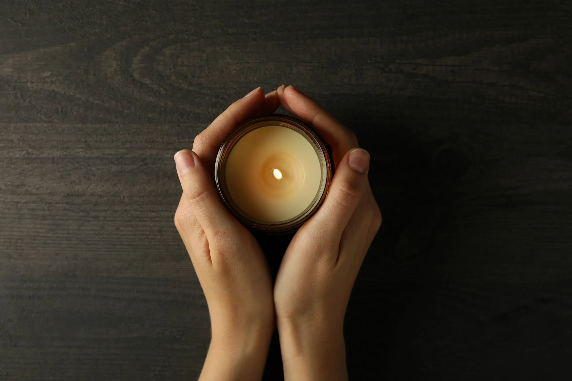 Mourning candles in hands, on a dark background.